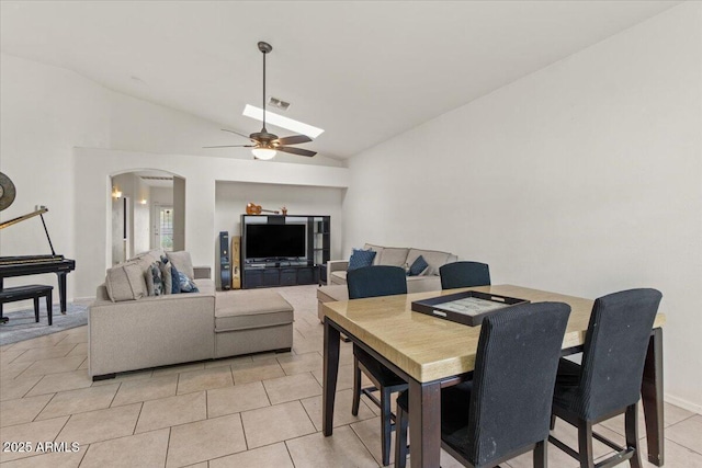 dining area featuring visible vents, a ceiling fan, arched walkways, vaulted ceiling with skylight, and light tile patterned floors