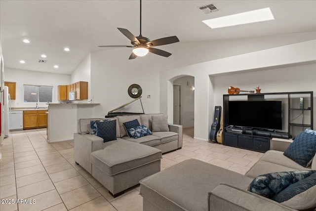 living area featuring visible vents, arched walkways, a ceiling fan, and vaulted ceiling