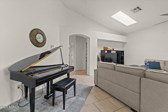 living room with visible vents, high vaulted ceiling, arched walkways, a skylight, and light tile patterned floors