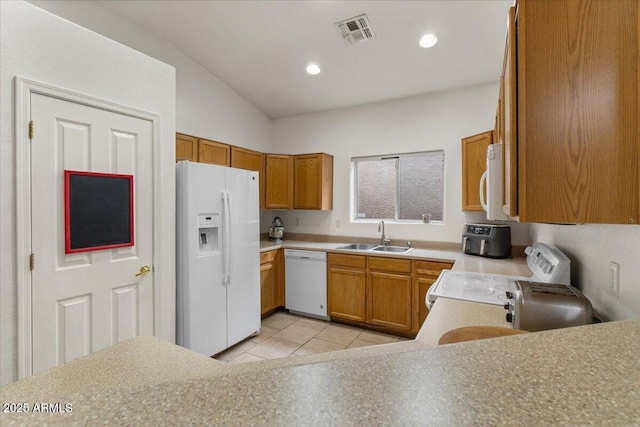 kitchen featuring visible vents, light countertops, brown cabinetry, white appliances, and a sink