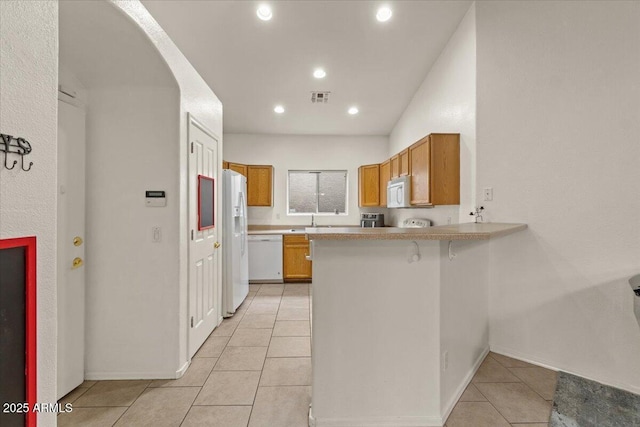 kitchen with white appliances, a peninsula, arched walkways, and light countertops