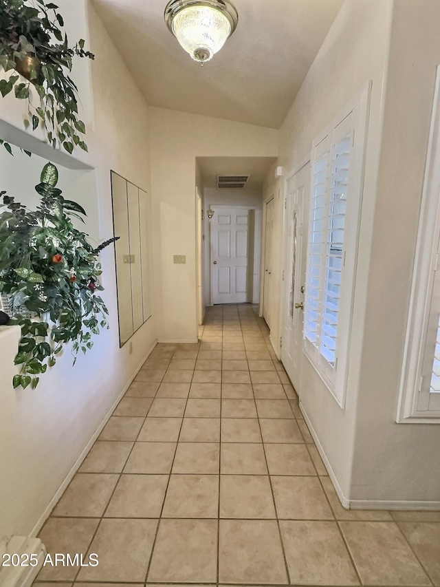 hall featuring visible vents, baseboards, and light tile patterned floors