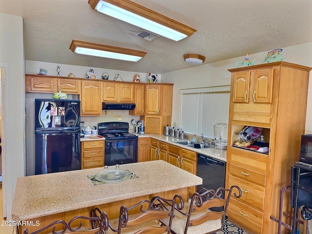 kitchen featuring under cabinet range hood, a sink, a kitchen breakfast bar, light countertops, and black appliances