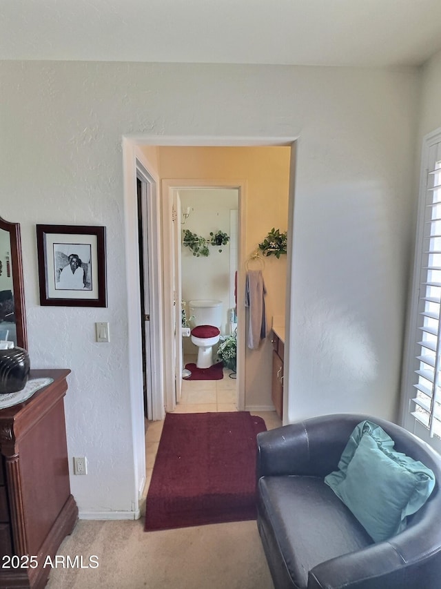 sitting room with light carpet, baseboards, and a textured wall