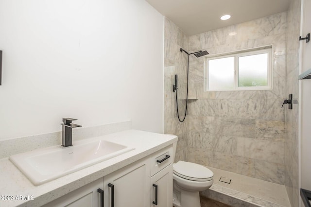 bathroom featuring tiled shower, vanity, and toilet