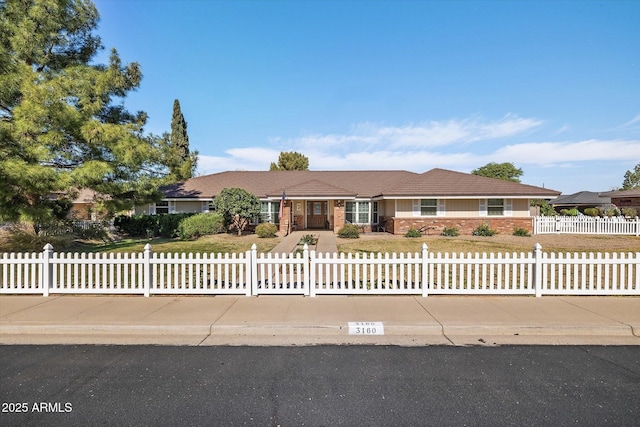 ranch-style home featuring a fenced front yard and brick siding