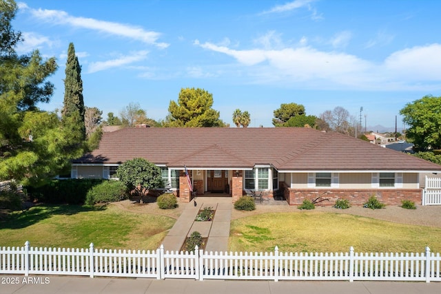 ranch-style house with a fenced front yard, a tile roof, and brick siding