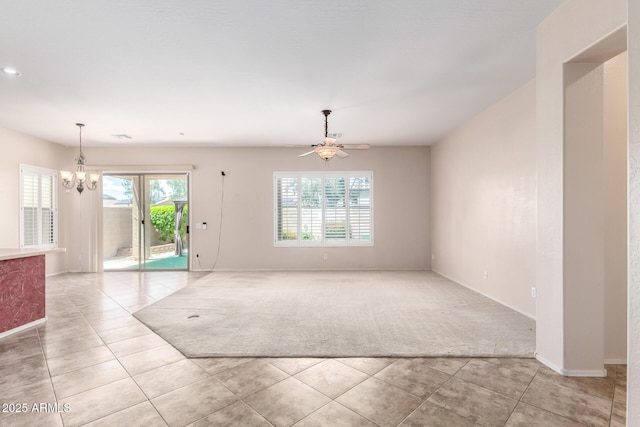 18072 W Paradise Ln, Surprise, AZ 85388 - spare room with baseboards, ceiling fan with notable chandelier, light tile patterned flooring, and light carpet