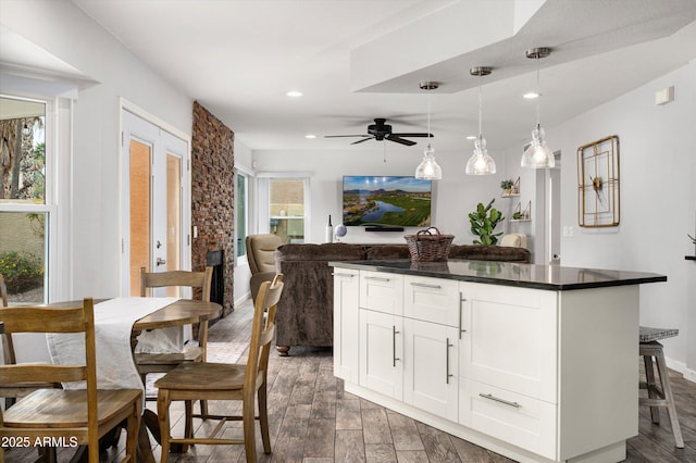 kitchen with white cabinetry, a center island, ceiling fan, hanging light fixtures, and a kitchen breakfast bar