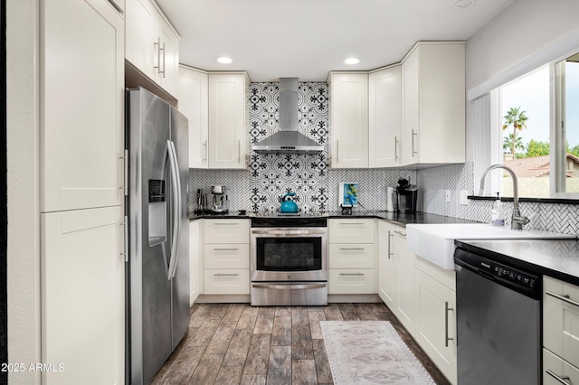 kitchen with backsplash, white cabinets, sink, wall chimney exhaust hood, and stainless steel appliances