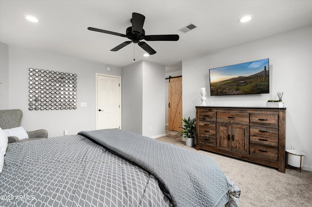 carpeted bedroom with a barn door and ceiling fan