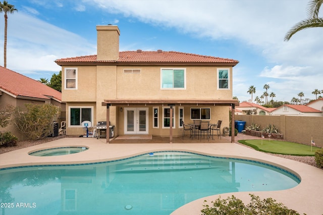 back of property featuring a patio area, french doors, and a pool with hot tub