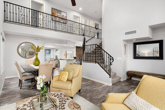 living room with dark hardwood / wood-style floors, ceiling fan, and a high ceiling