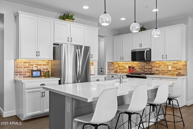 14573 W Reade Ave, Litchfield Park, AZ 85340 - kitchen with appliances with stainless steel finishes, recessed lighting, a kitchen island with sink, a kitchen breakfast bar, and backsplash