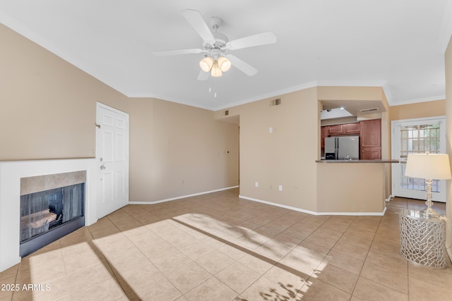 unfurnished living room featuring a tile fireplace, ceiling fan, crown molding, and light tile patterned flooring