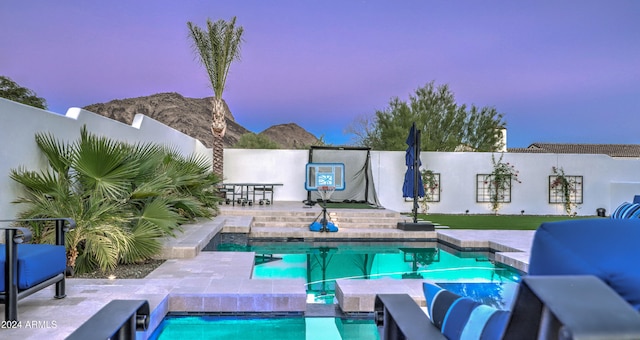 pool at dusk featuring a patio