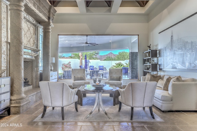 living room featuring ceiling fan, a high ceiling, beamed ceiling, and decorative columns