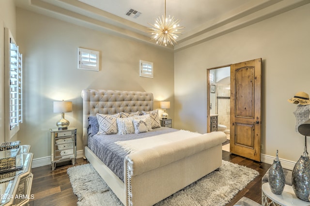 bedroom with dark wood-type flooring, ensuite bathroom, a chandelier, and a tray ceiling