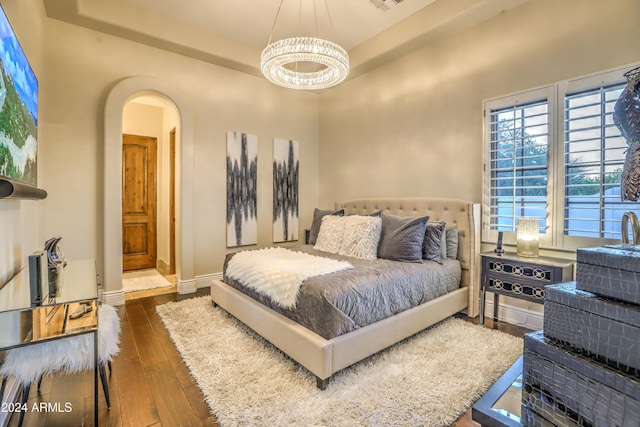 bedroom with dark hardwood / wood-style flooring and a chandelier