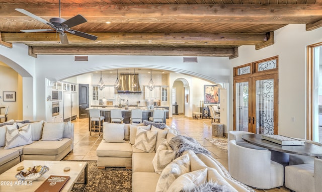 tiled living room featuring a wealth of natural light, wood ceiling, ceiling fan, and beam ceiling