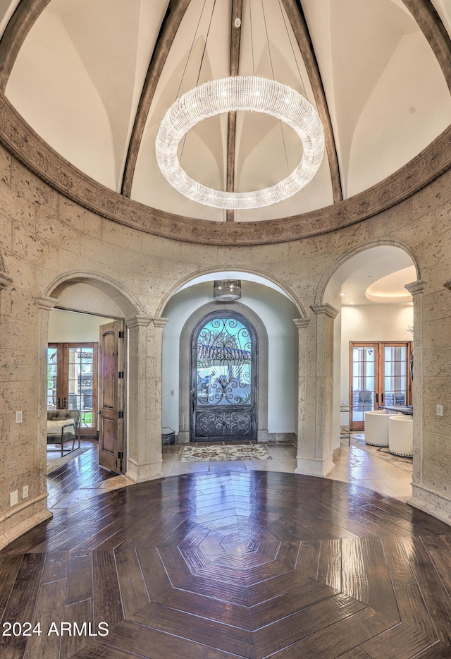 foyer featuring decorative columns, french doors, a healthy amount of sunlight, and beamed ceiling