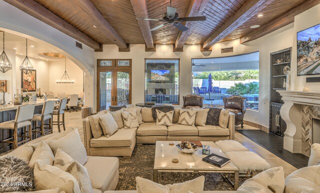 living room featuring ceiling fan with notable chandelier, beamed ceiling, and wooden ceiling