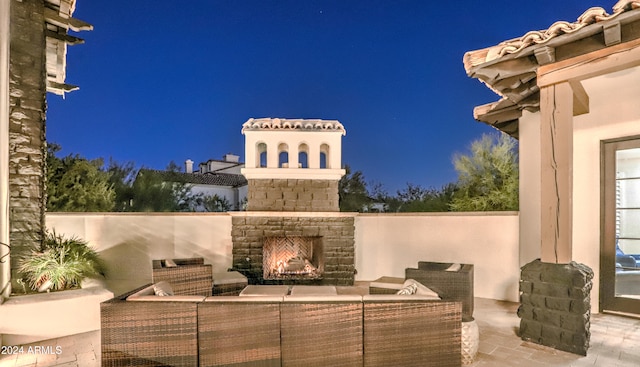 patio at night featuring an outdoor living space with a fireplace