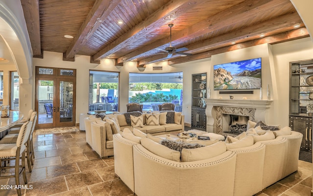 living room featuring beamed ceiling, ceiling fan, wood ceiling, a high end fireplace, and french doors