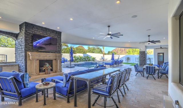 view of patio featuring ceiling fan and an outdoor living space with a fireplace