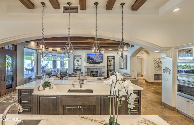 kitchen with a healthy amount of sunlight, dark brown cabinetry, sink, and beam ceiling