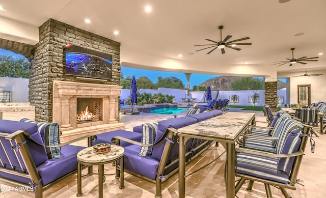 view of patio with ceiling fan and an outdoor living space with a fireplace