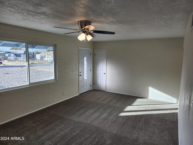 carpeted foyer with ceiling fan, brick wall, and a textured ceiling