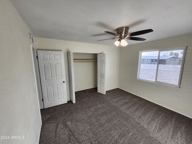 unfurnished bedroom featuring ceiling fan, a closet, and dark colored carpet