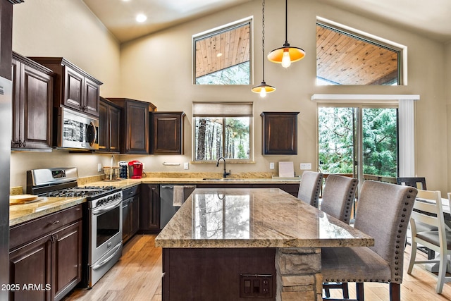 kitchen with pendant lighting, appliances with stainless steel finishes, light stone countertops, and a sink