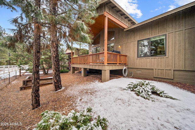 yard layered in snow with a wooden deck and fence