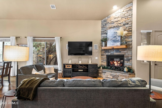 living room with visible vents, a fireplace, and wood finished floors