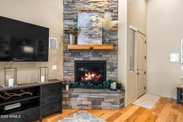 living room with a stone fireplace and wood finished floors