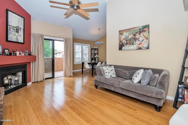 5640 E Bell Rd Unit 1099, Scottsdale, AZ 85254 - living area featuring light wood finished floors, ceiling fan, a fireplace, vaulted ceiling, and a chandelier