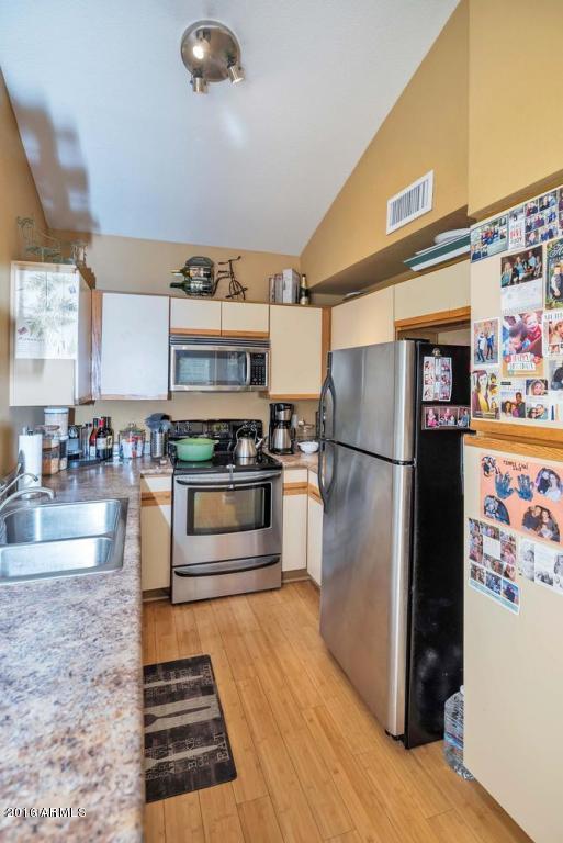 5640 E Bell Rd Unit 1099, Scottsdale, AZ 85254 - kitchen featuring appliances with stainless steel finishes, vaulted ceiling, light countertops, white cabinetry, and light wood-style flooring