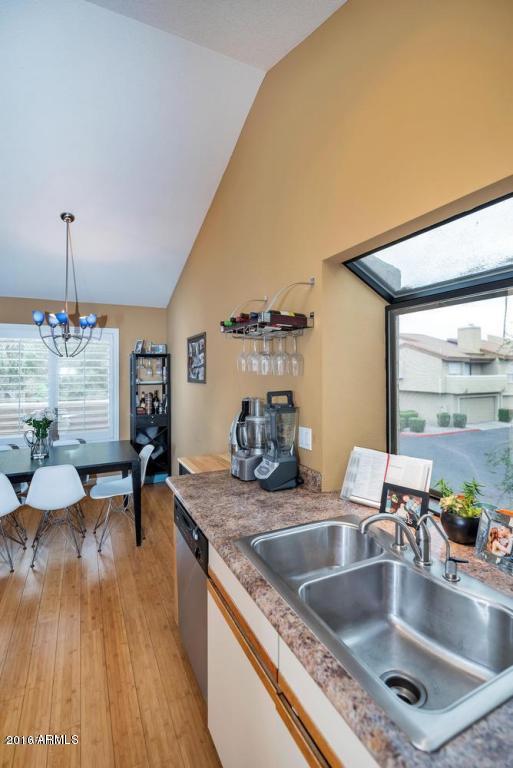 5640 E Bell Rd Unit 1099, Scottsdale, AZ 85254 - kitchen with stainless steel dishwasher, light wood-style floors, a chandelier, decorative light fixtures, and light countertops