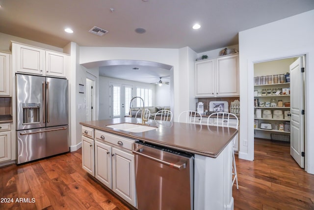 kitchen featuring sink, white cabinets, a kitchen island with sink, stainless steel appliances, and dark wood-type flooring