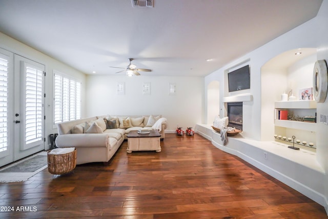 living room with dark hardwood / wood-style flooring, built in features, and ceiling fan