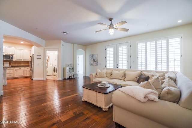 living room with dark hardwood / wood-style flooring, washer / dryer, and ceiling fan