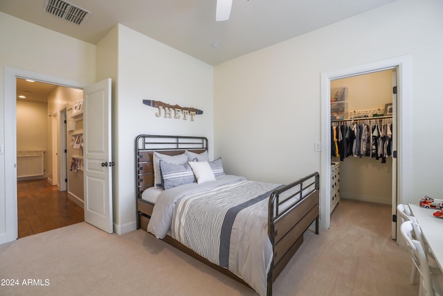 carpeted bedroom with ceiling fan, a walk in closet, and a closet