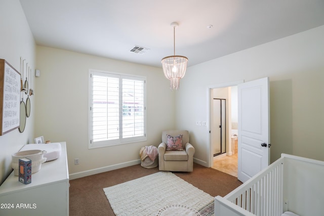 carpeted bedroom with an inviting chandelier and a crib