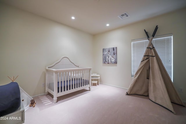 bedroom with light carpet and a nursery area