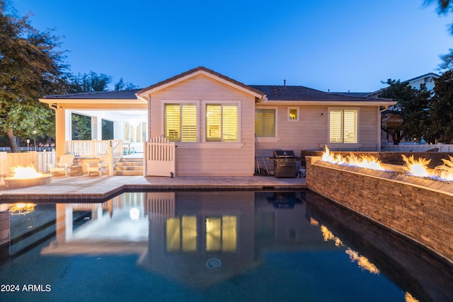 back house at dusk featuring a patio and an outdoor fire pit