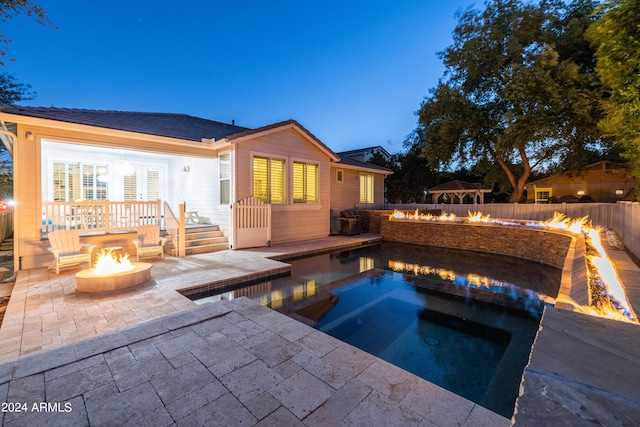 pool at dusk with a patio, an in ground hot tub, and a fire pit