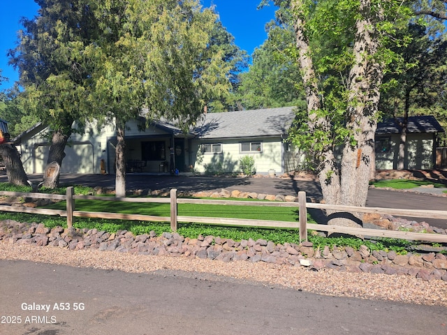 view of front facade with aphalt driveway, a fenced front yard, and a shingled roof