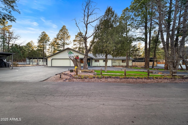 view of front of house with aphalt driveway, an attached garage, and fence